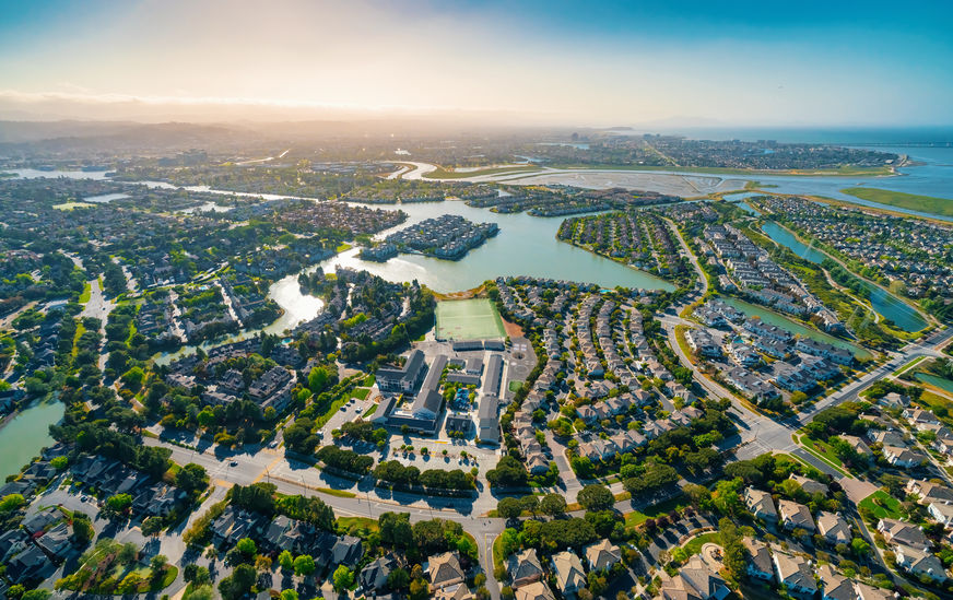 Aerial view of residential real estate homes in Foster City, CA. Waterways intersect the neighborhoods.