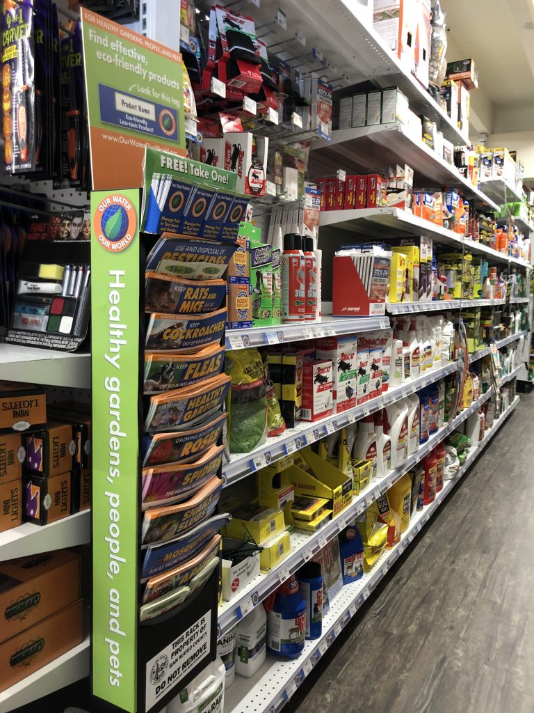 Rack of inlets containing flyers and brochures about pest management. This is placed next to an aisle of pest management products.